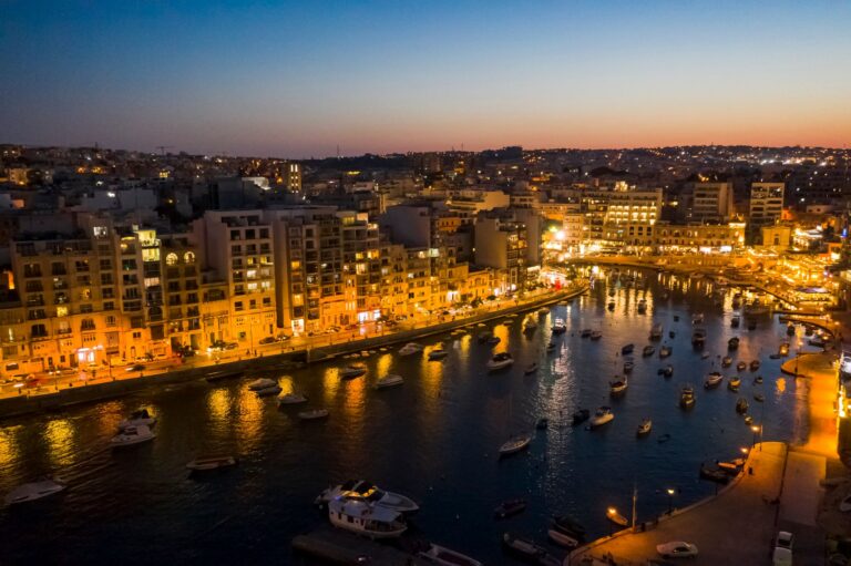 Sliema waterfront in Malta at twilight, with illuminated buildings along the harbor