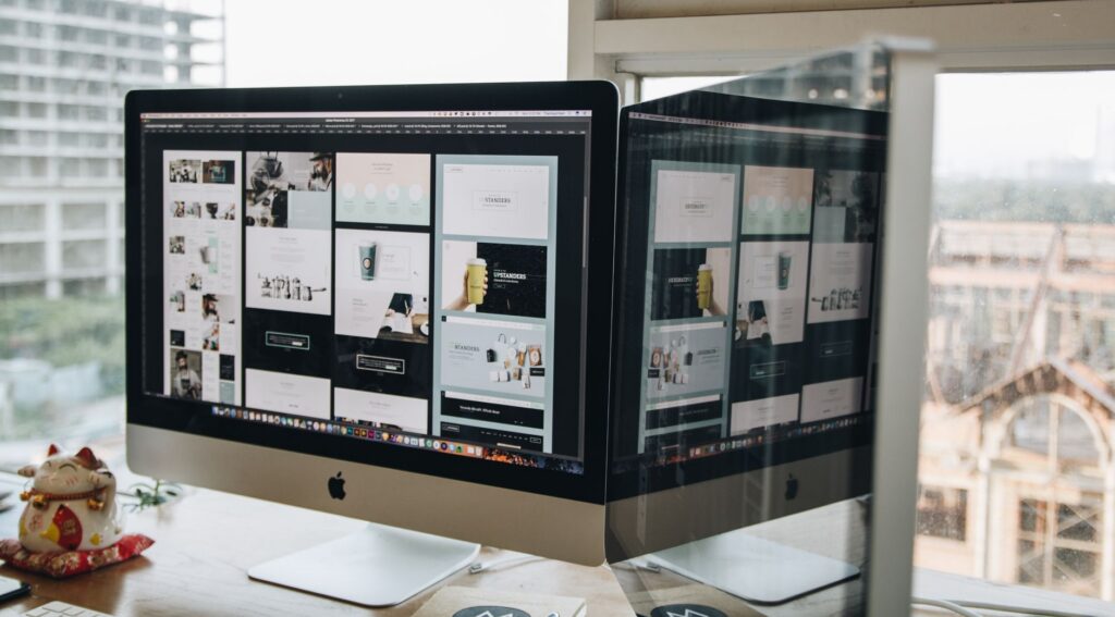 Dual monitors displaying web design work in a modern office