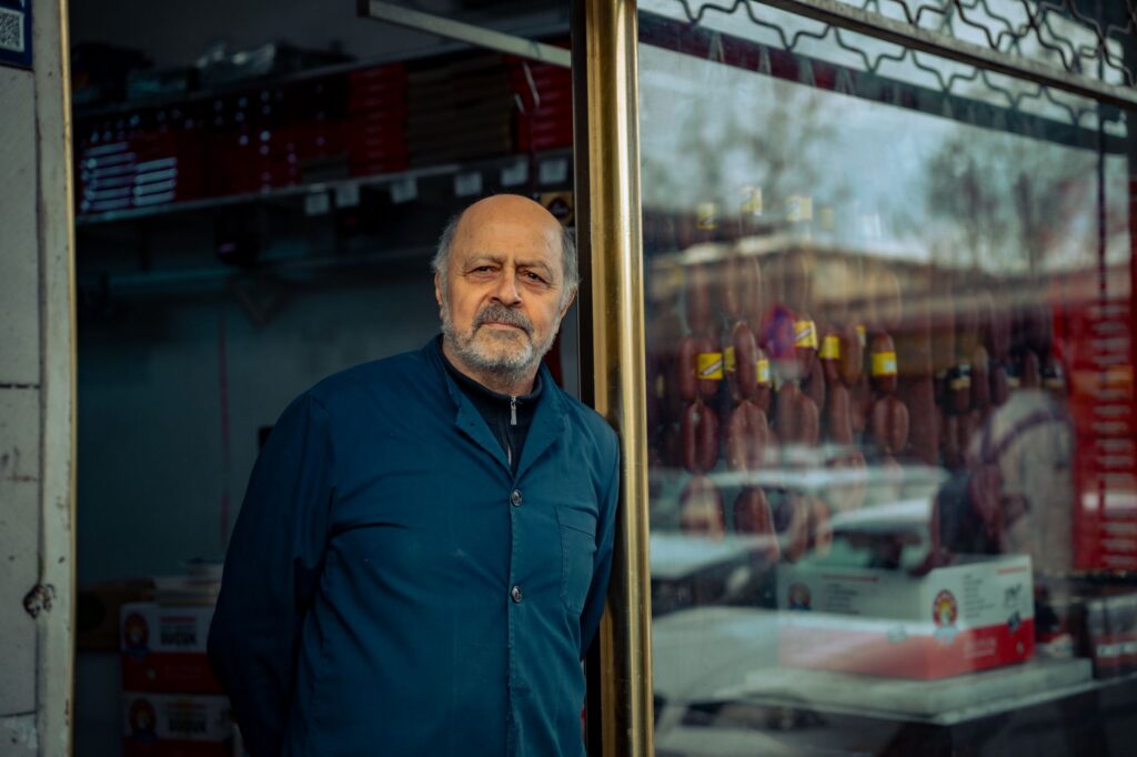 Senior small business owner standing outside his urban storefront
