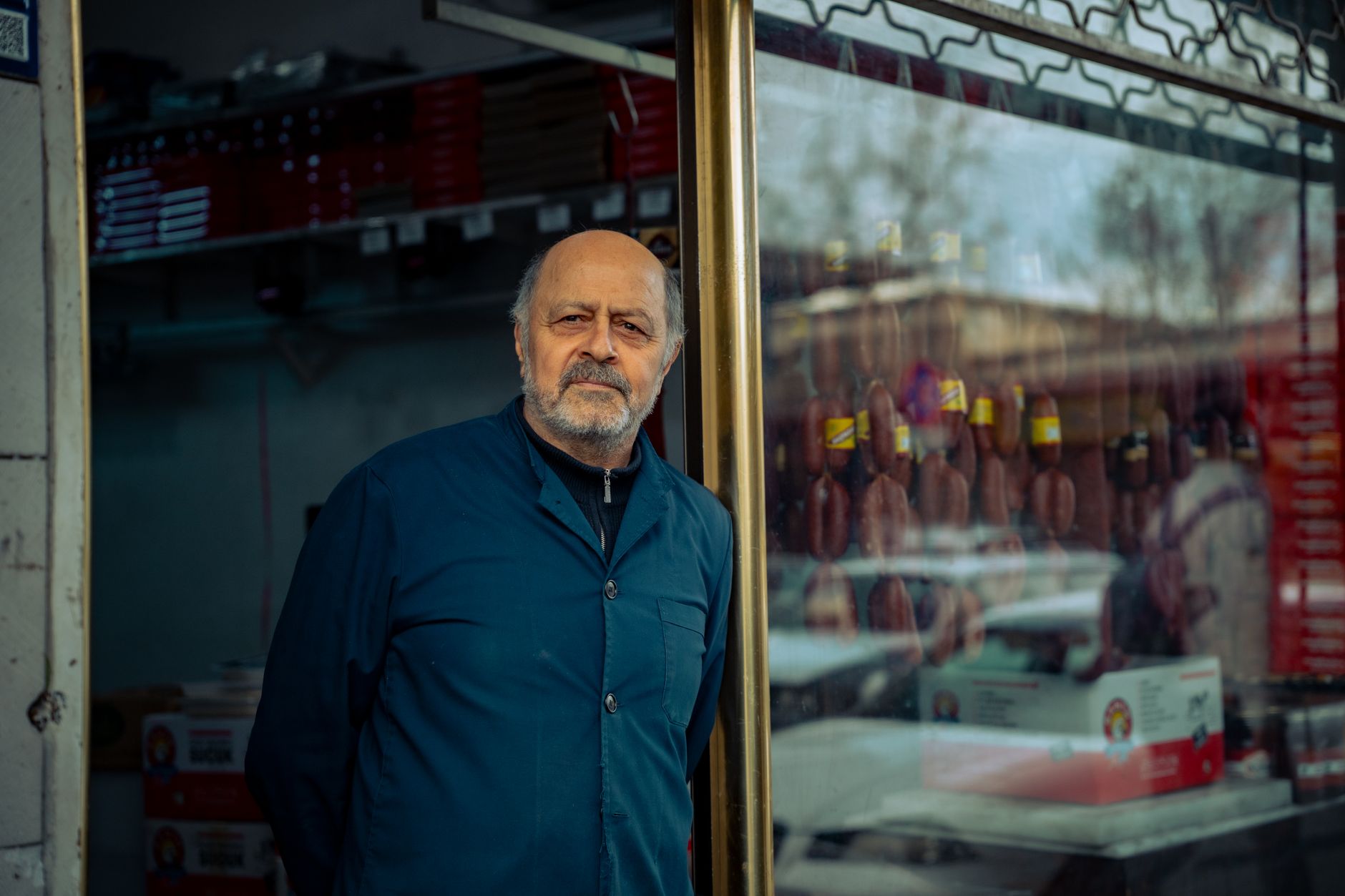 Senior small business owner standing outside his urban storefront