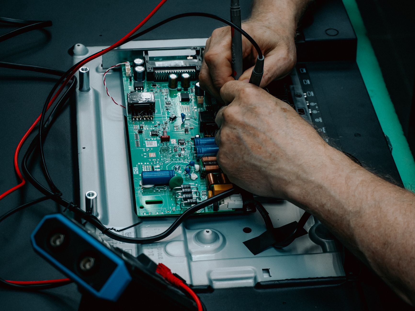 Close-up of hands repairing a circuit board, illustrating careful website maintenance.