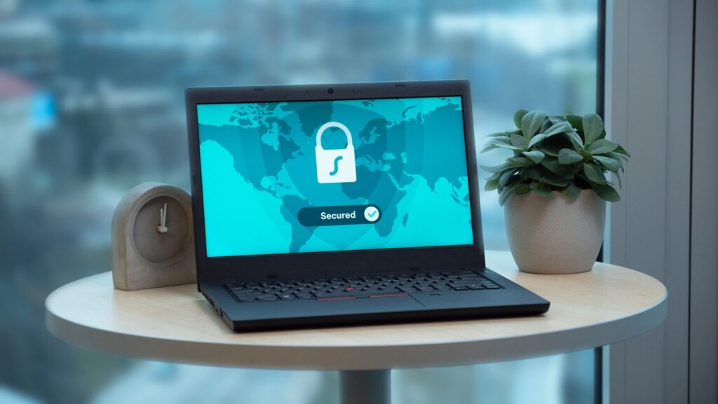 Laptop displaying a security lock icon beside a potted plant and clock