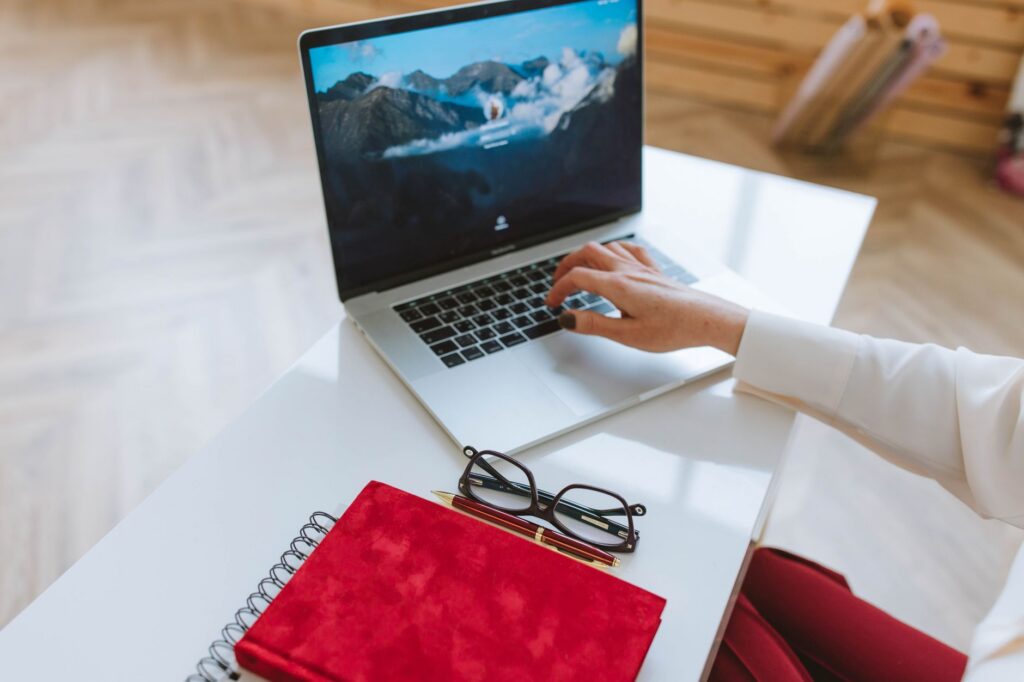 Entrepreneur working on a laptop beside a notebook and glasses at a clean desk