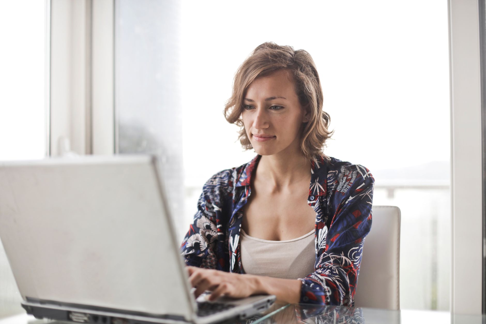 Woman typing on a laptop in a bright home office