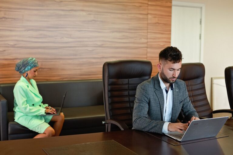 Two business professionals using laptops in a modern office
