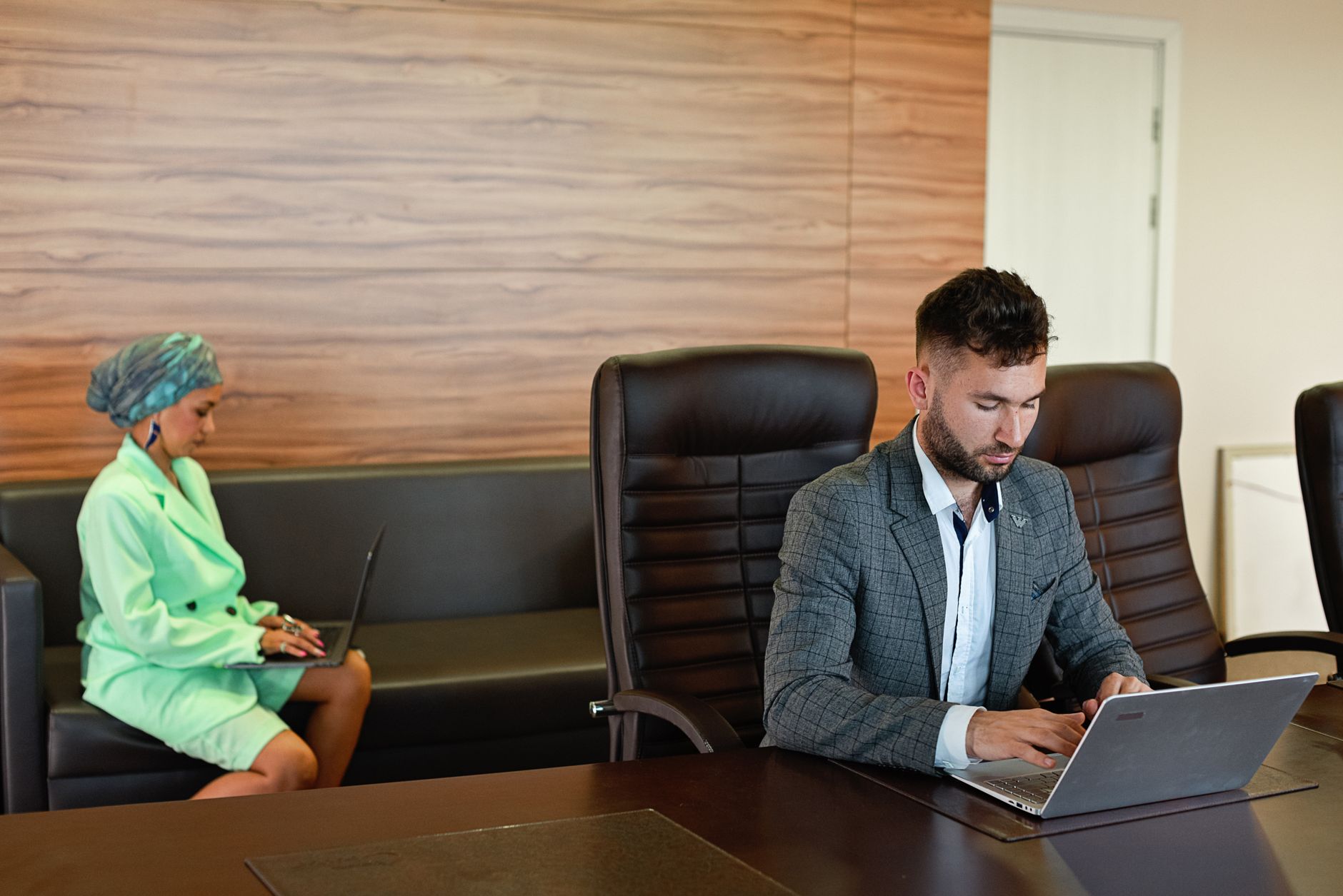 Two business professionals using laptops in a modern office