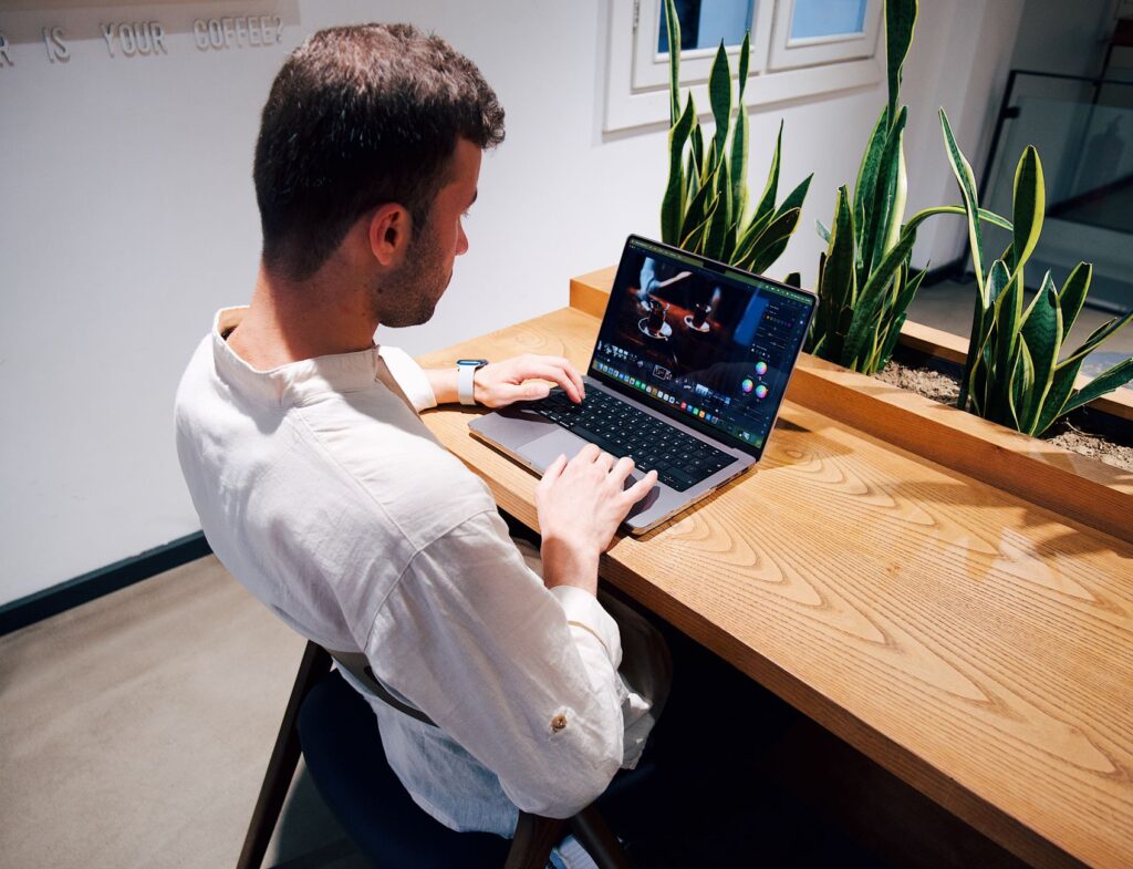 Professional working on a laptop at a modern desk with plants